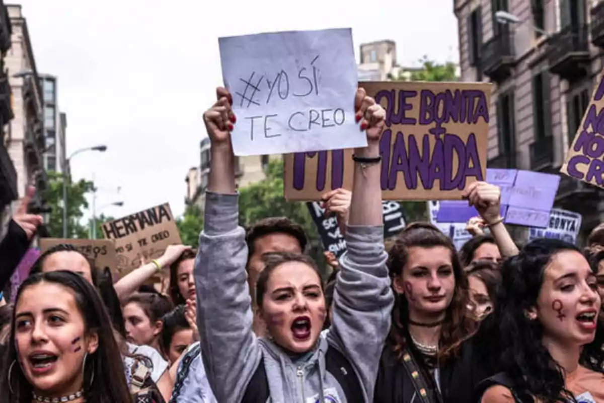 Personas participando en una manifestación con pancartas y carteles, una de ellas sostiene un cartel que dice "#YoSíTeCreo".