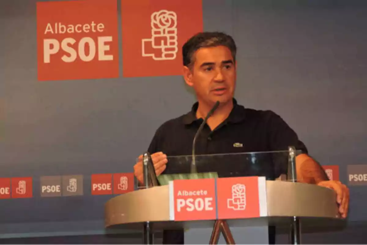 Hombre hablando en un podio con el logotipo del PSOE de Albacete en el fondo.