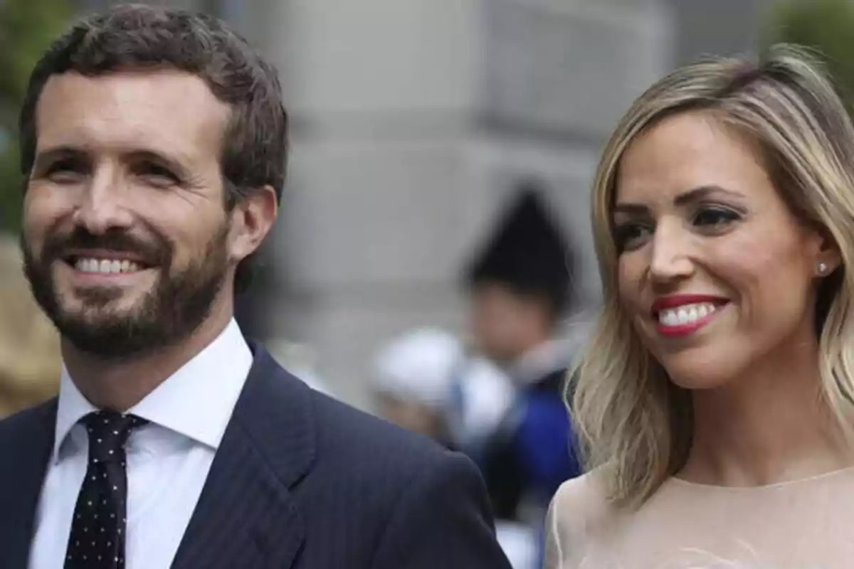 Una pareja sonriente vestida formalmente en un evento al aire libre.