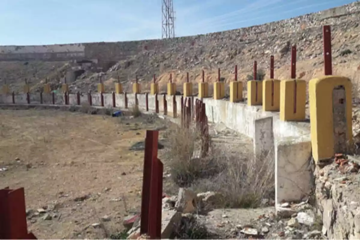 Una plaza de toros abandonada con gradas deterioradas y postes de madera.