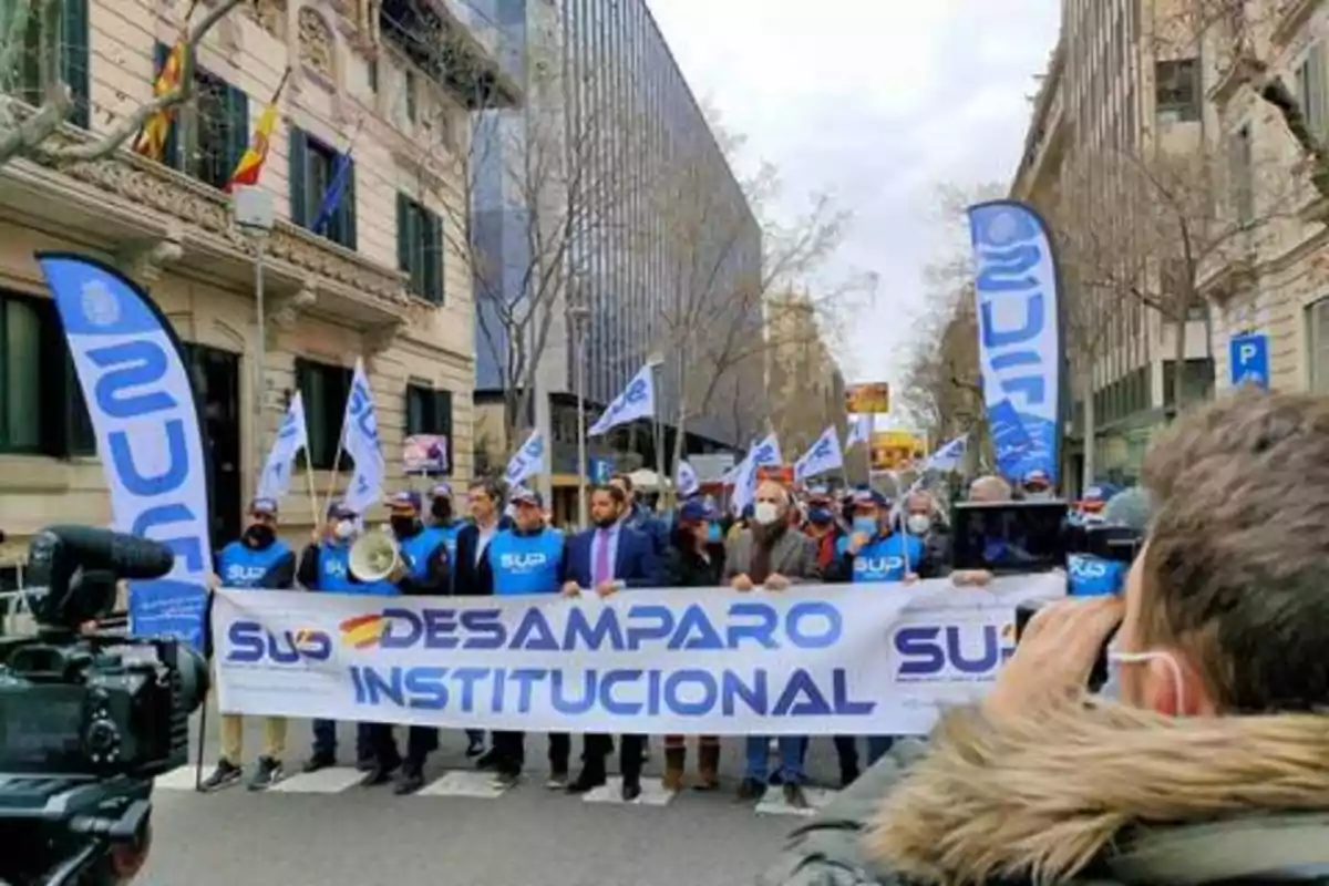 Manifestación de personas con pancartas y banderas en una calle de la ciudad.