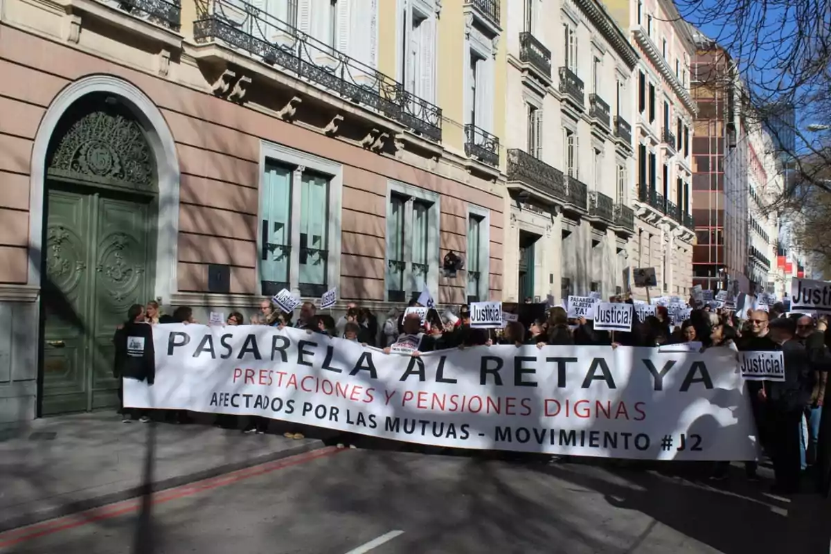 Manifestación en la calle con personas sosteniendo una pancarta que dice 