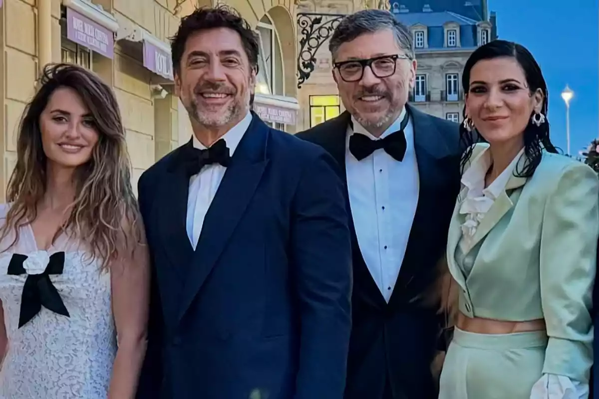 Cuatro personas elegantemente vestidas posan sonrientes al aire libre frente a un edificio clásico Cuatro personas elegantemente vestidas posan sonrientes al aire libre frente a un edificio clásico