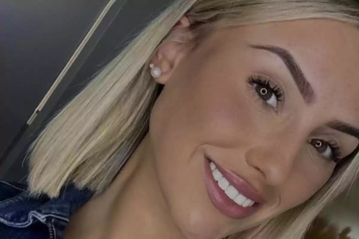 Mujer joven de cabello rubio corto sonriendo y usando aretes de perla Mujer joven de cabello rubio corto sonriendo y usando aretes de perla