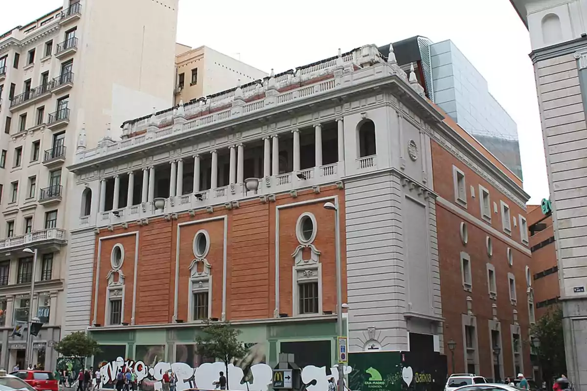 Edificio histórico de ladrillo y piedra blanca con ventanas ovaladas y columnas en la parte superior ubicado en una calle concurrida de la ciudad Edificio histórico de ladrillo y piedra blanca con ventanas ovaladas y columnas en la parte superior ubicado en una calle concurrida de la ciudad
