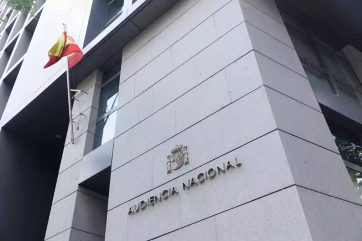 Fachada de un edificio moderno con la bandera de España y el letrero Audiencia Nacional