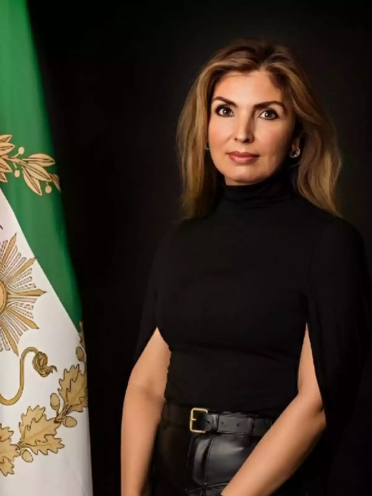 Mujer de cabello rubio y suelto vestida de negro posando junto a una bandera mexicana sobre fondo oscuro Mujer de cabello rubio y suelto vestida de negro posando junto a una bandera mexicana sobre fondo oscuro