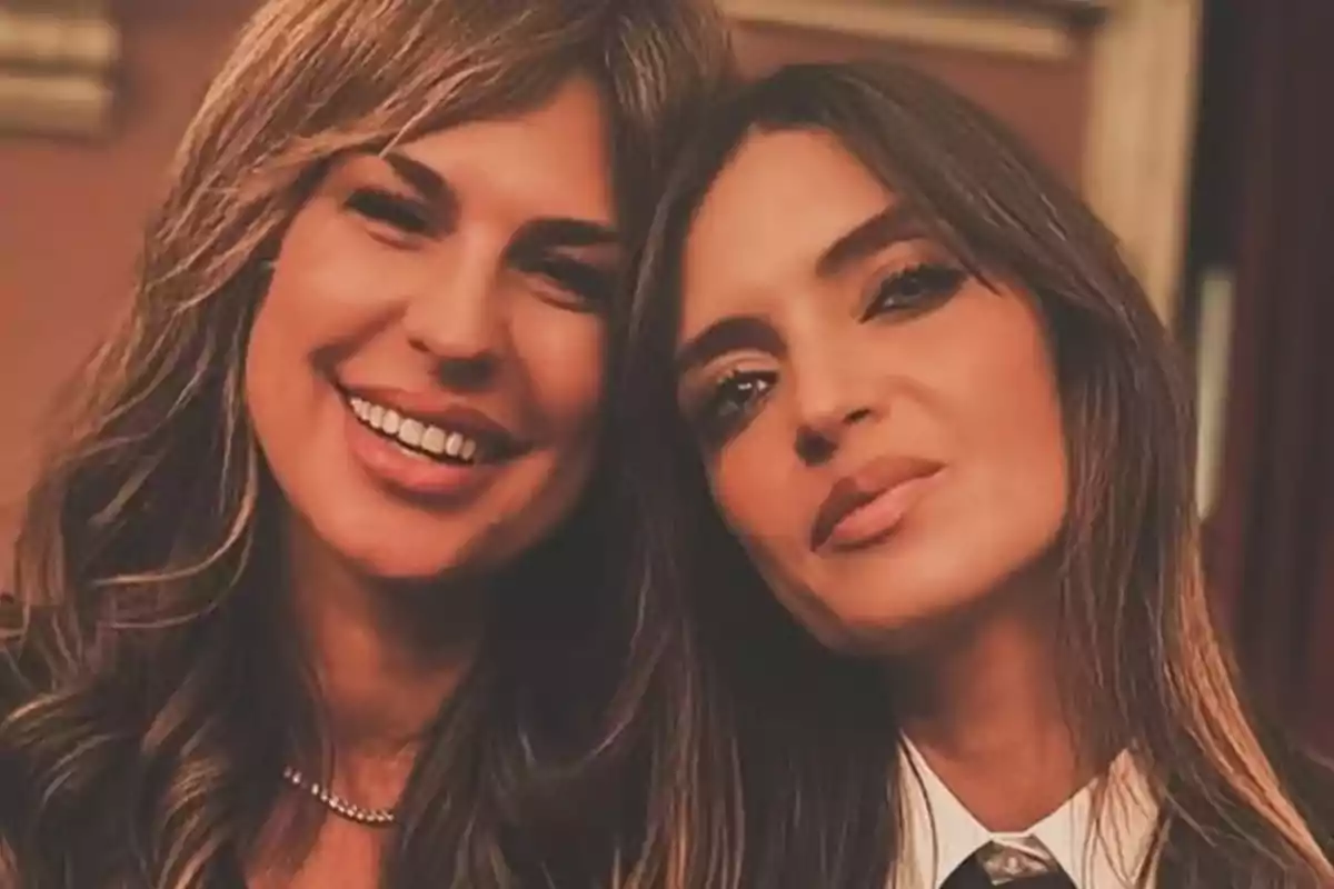Dos mujeres posan juntas y sonríen en una fotografía tomada en un ambiente interior cálido. Dos mujeres posan juntas y sonríen en una fotografía tomada en un ambiente interior cálido.