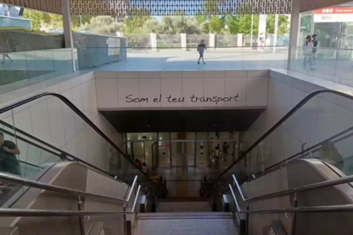Entrada a una estación de metro con escaleras eléctricas y un letrero en catalán que dice Som el teu transport