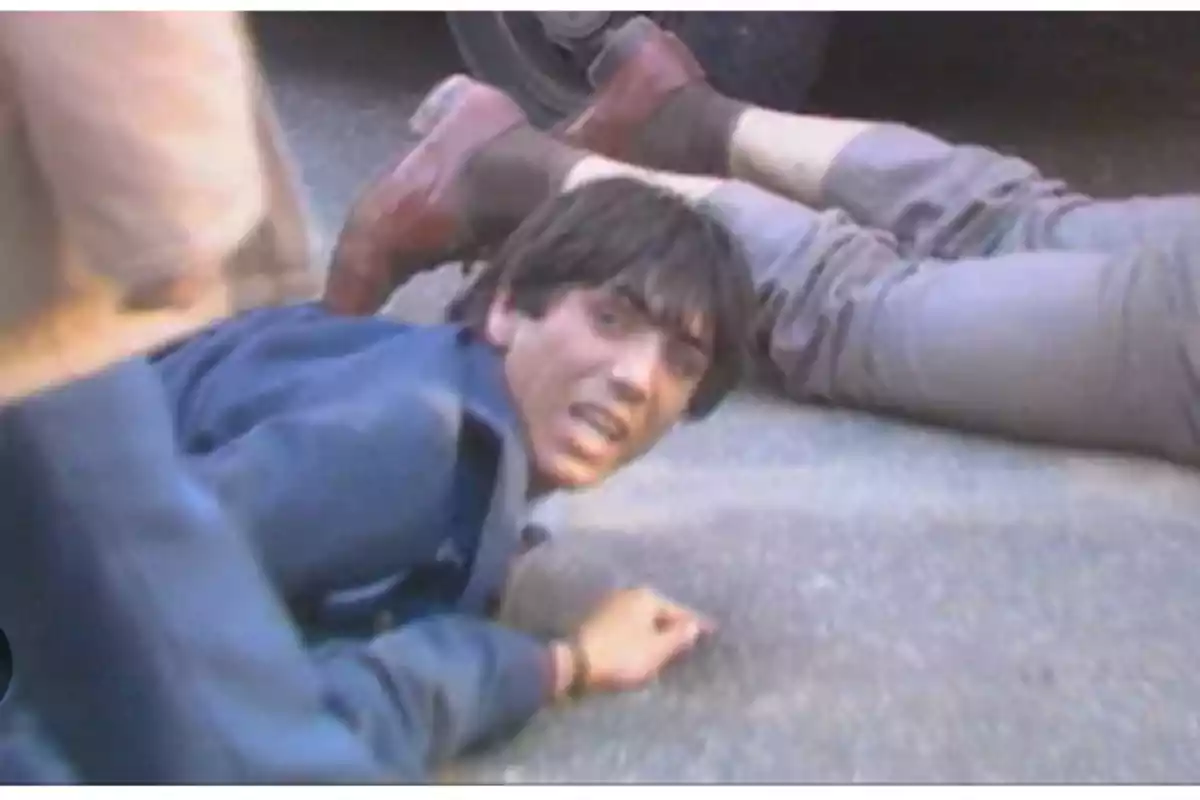 Joven tirado en el suelo con expresión de angustia junto a otra persona tendida en el pavimento Joven tirado en el suelo con expresión de angustia junto a otra persona tendida en el pavimento