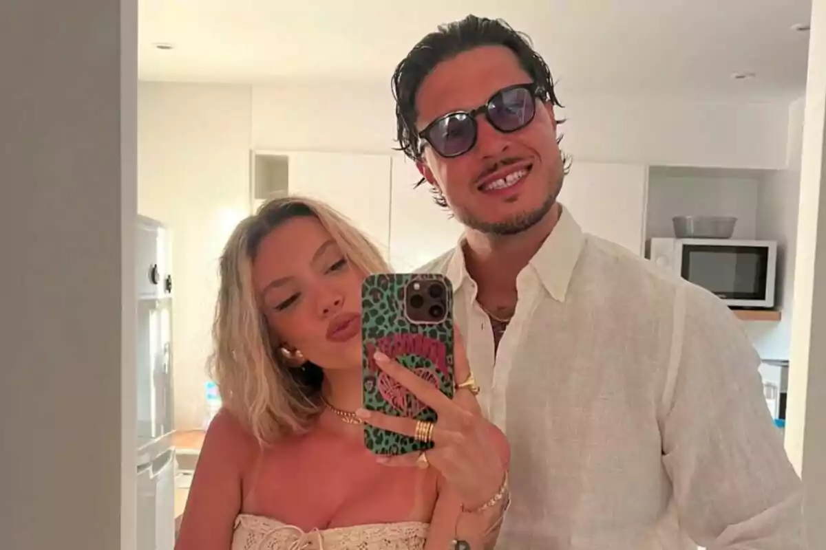 Una pareja joven -formada por Alejandra Rubio y Carlo Costanzia- se toma una selfie frente a un espejo en una cocina moderna, ambos sonríen y visten ropa clara y veraniega. Una pareja joven -formada por Alejandra Rubio y Carlo Costanzia- se toma una selfie frente a un espejo en una cocina moderna, ambos sonríen y visten ropa clara y veraniega.