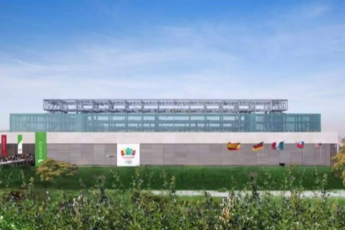 Edificio moderno con fachada de vidrio y varias banderas de diferentes países ondeando al frente en un área verde Edificio moderno con fachada de vidrio y varias banderas de diferentes países ondeando al frente en un área verde
