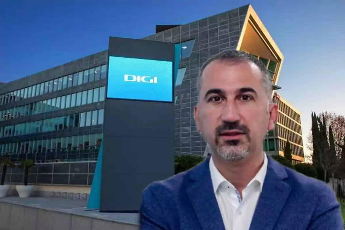 Hombre de cabello corto y barba con saco azul frente a edificio moderno con letrero de la empresa DIGI