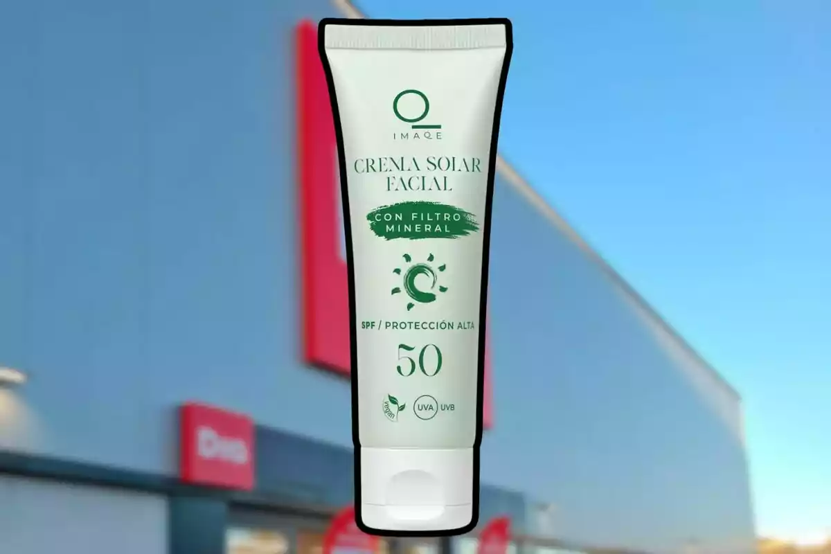 Envase de crema solar facial con filtro mineral SPF 50 sostenido frente a una tienda con fachada azul y letreros rojos. Envase de crema solar facial con filtro mineral SPF 50 sostenido frente a una tienda con fachada azul y letreros rojos.