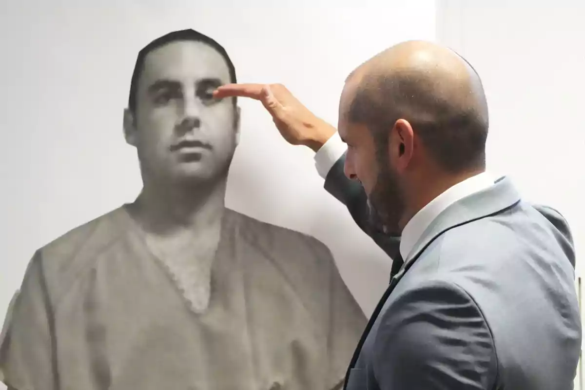 Hombre de traje señalando la cabeza de una fotografía en blanco y negro de otra persona Hombre de traje señalando la cabeza de una fotografía en blanco y negro de otra persona