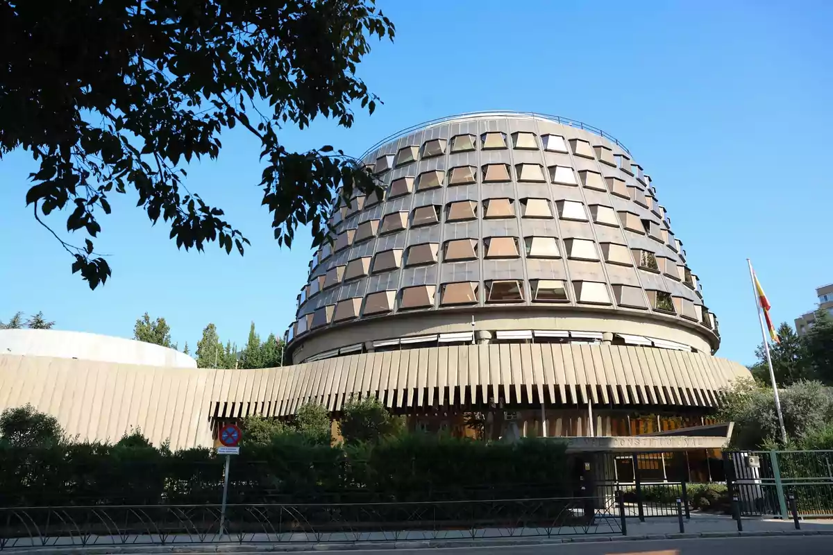 Edificio circular de varias plantas con ventanas inclinadas y una bandera de España ondeando a la derecha Edificio circular de varias plantas con ventanas inclinadas y una bandera de España ondeando a la derecha