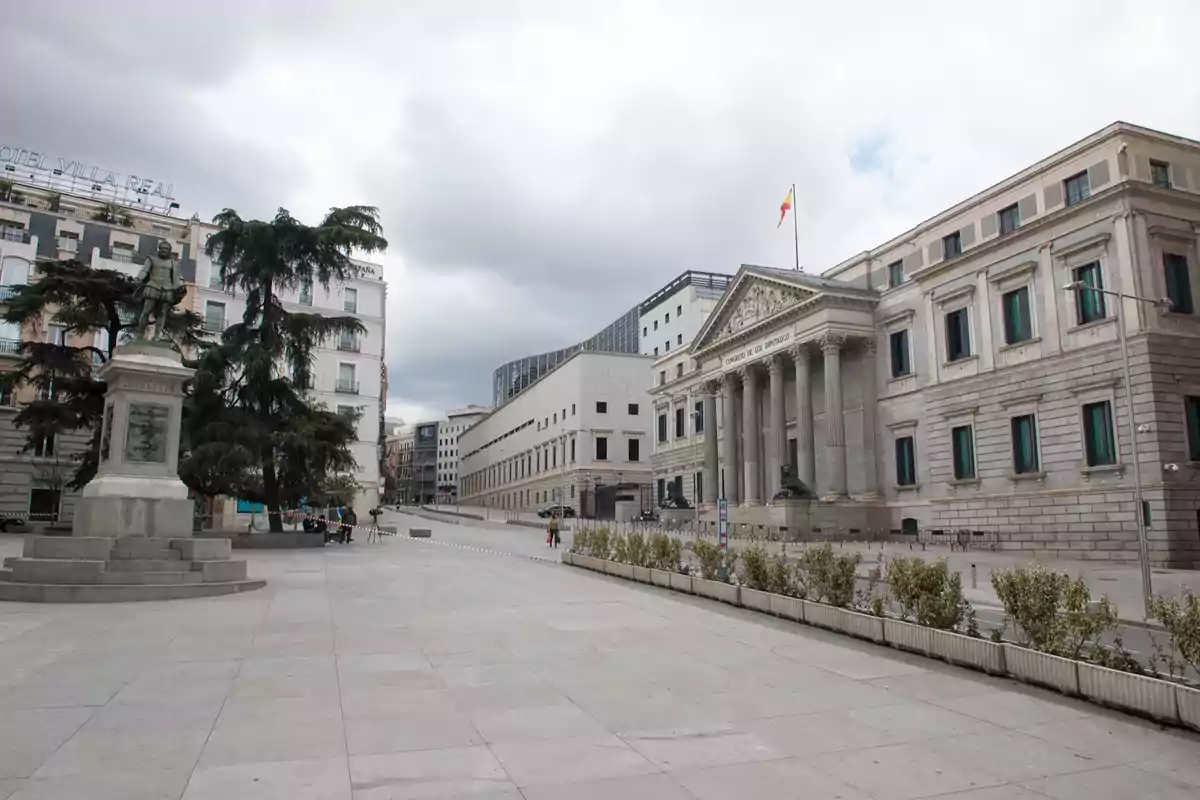 Edificio del Congreso de los Diputados en Madrid con una estatua y árboles en la plaza bajo un cielo nublado Edificio del Congreso de los Diputados en Madrid con una estatua y árboles en la plaza bajo un cielo nublado