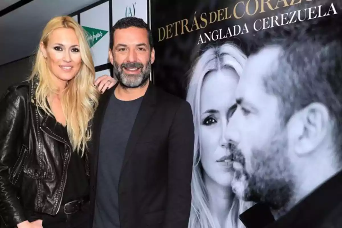 Una mujer rubia y un hombre de barba posan sonrientes frente a un cartel promocional en un evento. Una mujer rubia y un hombre de barba posan sonrientes frente a un cartel promocional en un evento.