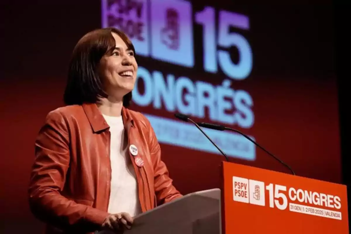 Mujer sonriente con chaqueta roja hablando en un podio durante el 15 Congreso del PSPV PSOE en Valencia Mujer sonriente con chaqueta roja hablando en un podio durante el 15 Congreso del PSPV PSOE en Valencia