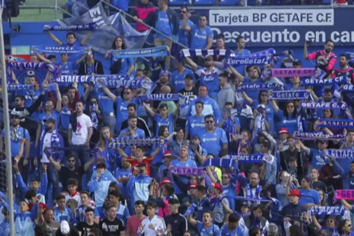 Aficionados del Getafe animando en las gradas con bufandas y camisetas azules Aficionados del Getafe animando en las gradas con bufandas y camisetas azules