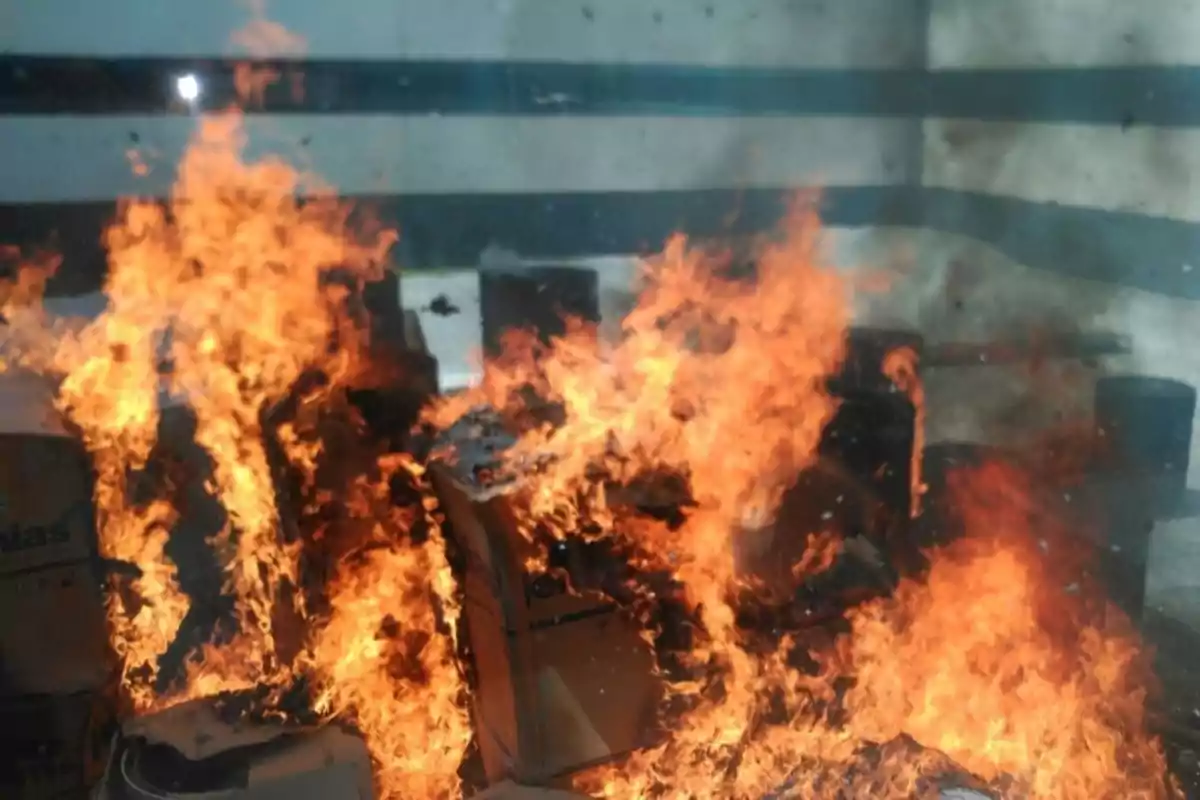 Fuego intenso consumiendo varias cajas de cartón en el interior de una habitación
