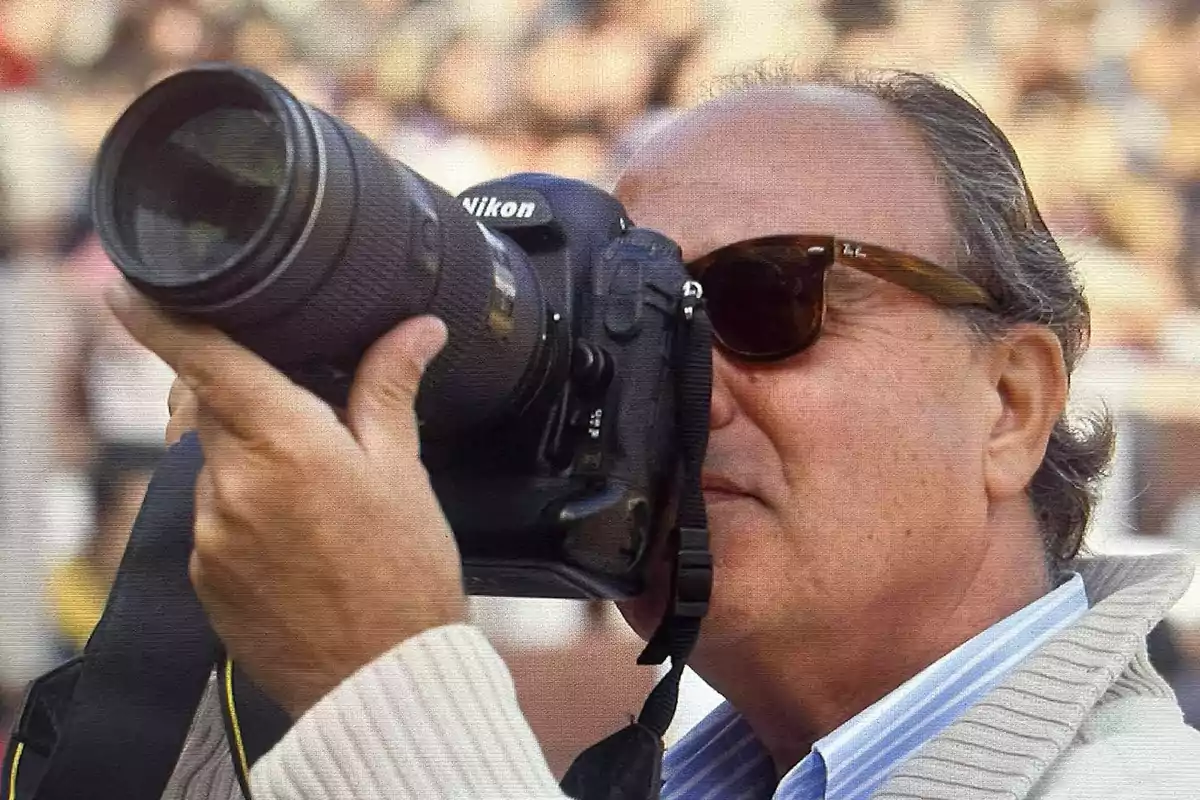 Hombre con gafas de sol usando una cámara profesional Nikon en un evento al aire libre Hombre con gafas de sol usando una cámara profesional Nikon en un evento al aire libre