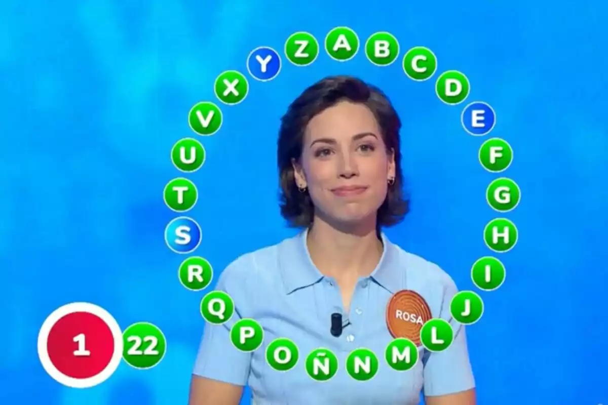 Rosa Rodríguez, concursante de un programa de televisión, con un círculo de letras alrededor y un marcador que muestra 22 respuestas correctas y una incorrecta. Rosa Rodríguez, concursante de un programa de televisión, con un círculo de letras alrededor y un marcador que muestra 22 respuestas correctas y una incorrecta.