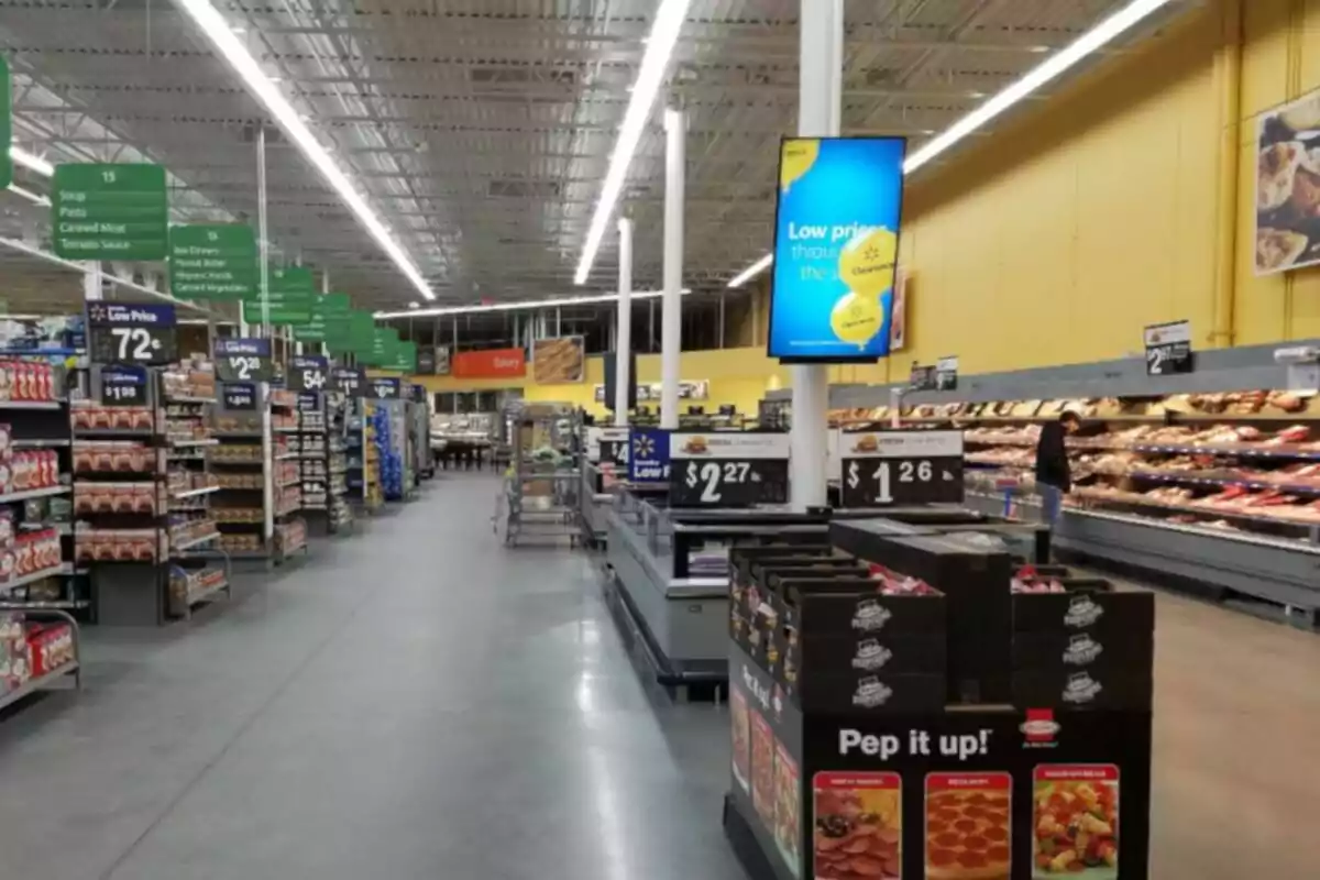 Pasillo de supermercado con estantes llenos de productos y señalización de precios bajos Pasillo de supermercado con estantes llenos de productos y señalización de precios bajos