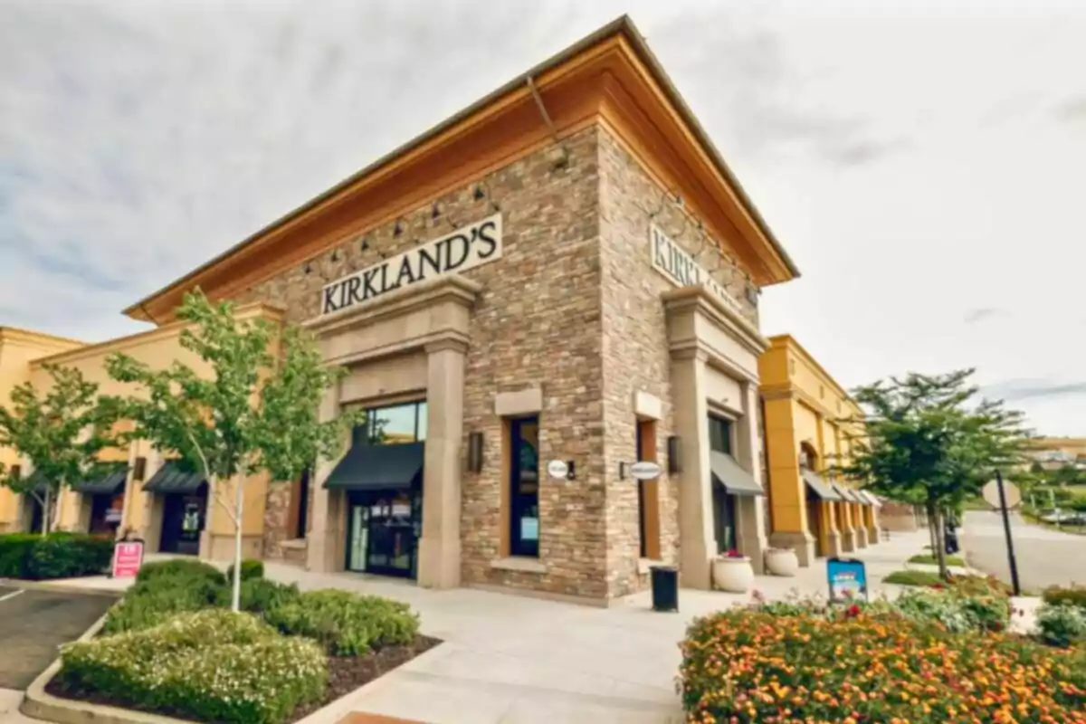 Fachada de una tienda Kirkland's en una esquina rodeada de plantas y árboles en un centro comercial Fachada de una tienda Kirkland's en una esquina rodeada de plantas y árboles en un centro comercial