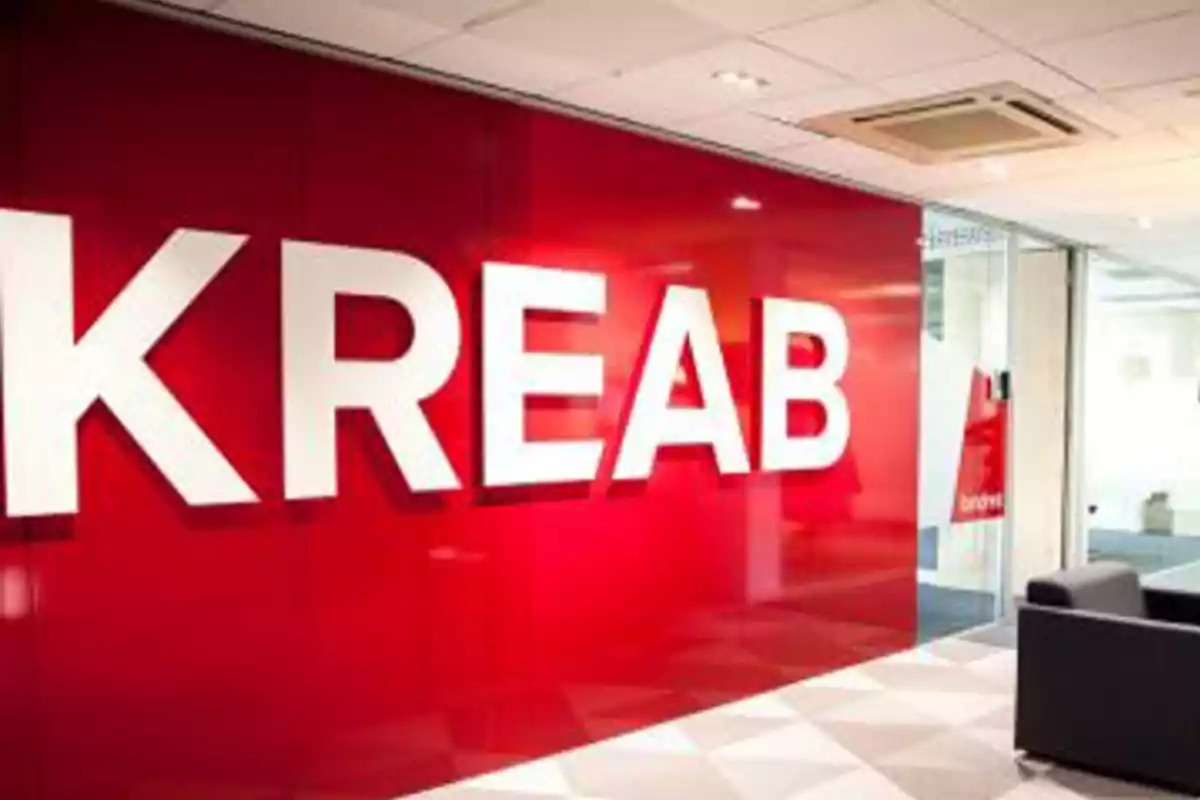 Pared roja con el logo de KREAB en letras grandes y blancas en una oficina moderna Pared roja con el logo de KREAB en letras grandes y blancas en una oficina moderna