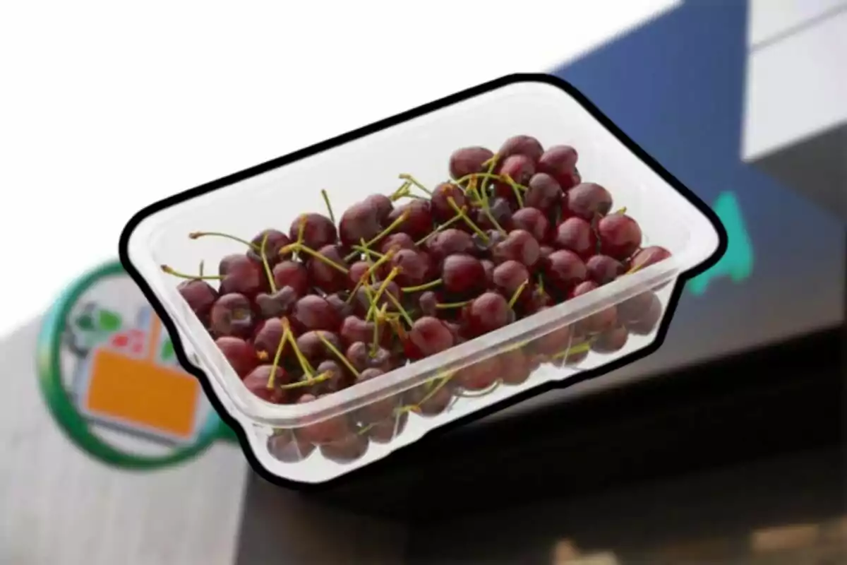 Charola de cerezas frescas en un envase de plástico frente a una tienda