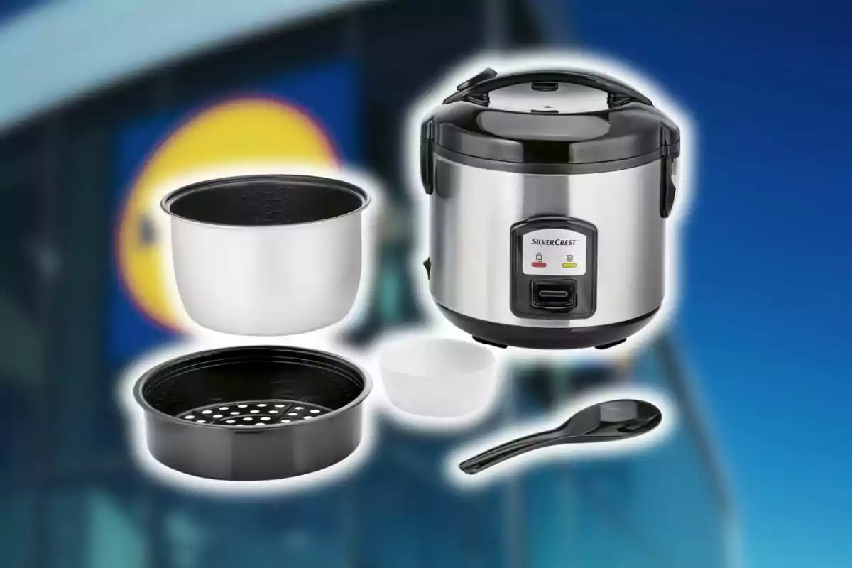 Olla arrocera eléctrica de Lidl con accesorios como recipiente interior, bandeja para vapor, taza medidora y cuchara sobre un fondo desenfocado de una tienda. Olla arrocera eléctrica de Lidl con accesorios como recipiente interior, bandeja para vapor, taza medidora y cuchara sobre un fondo desenfocado de una tienda.