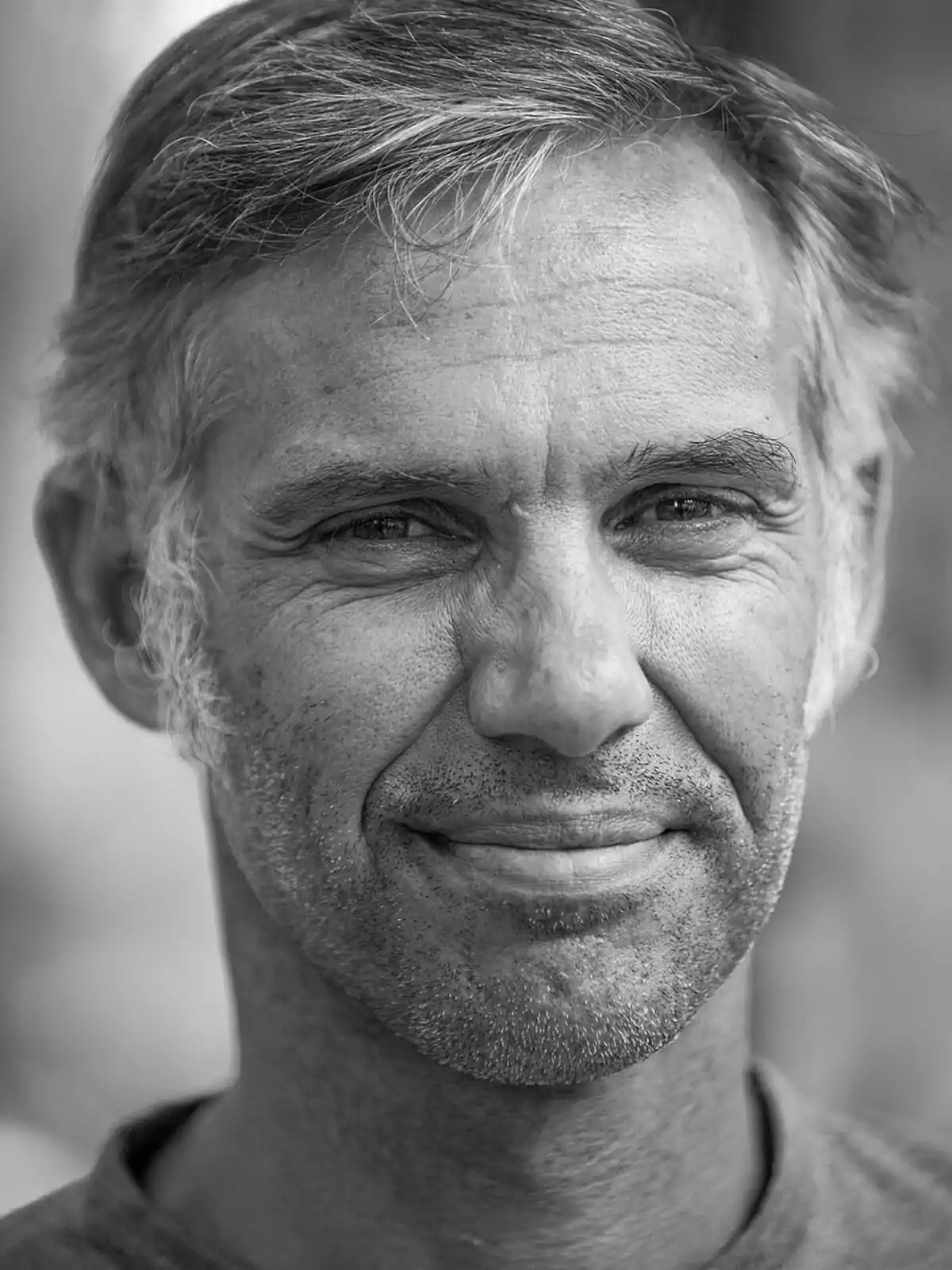 Hombre de mediana edad con cabello canoso y barba incipiente mirando a la cámara y sonriendo levemente en una fotografía en blanco y negro Hombre de mediana edad con cabello canoso y barba incipiente mirando a la cámara y sonriendo levemente en una fotografía en blanco y negro