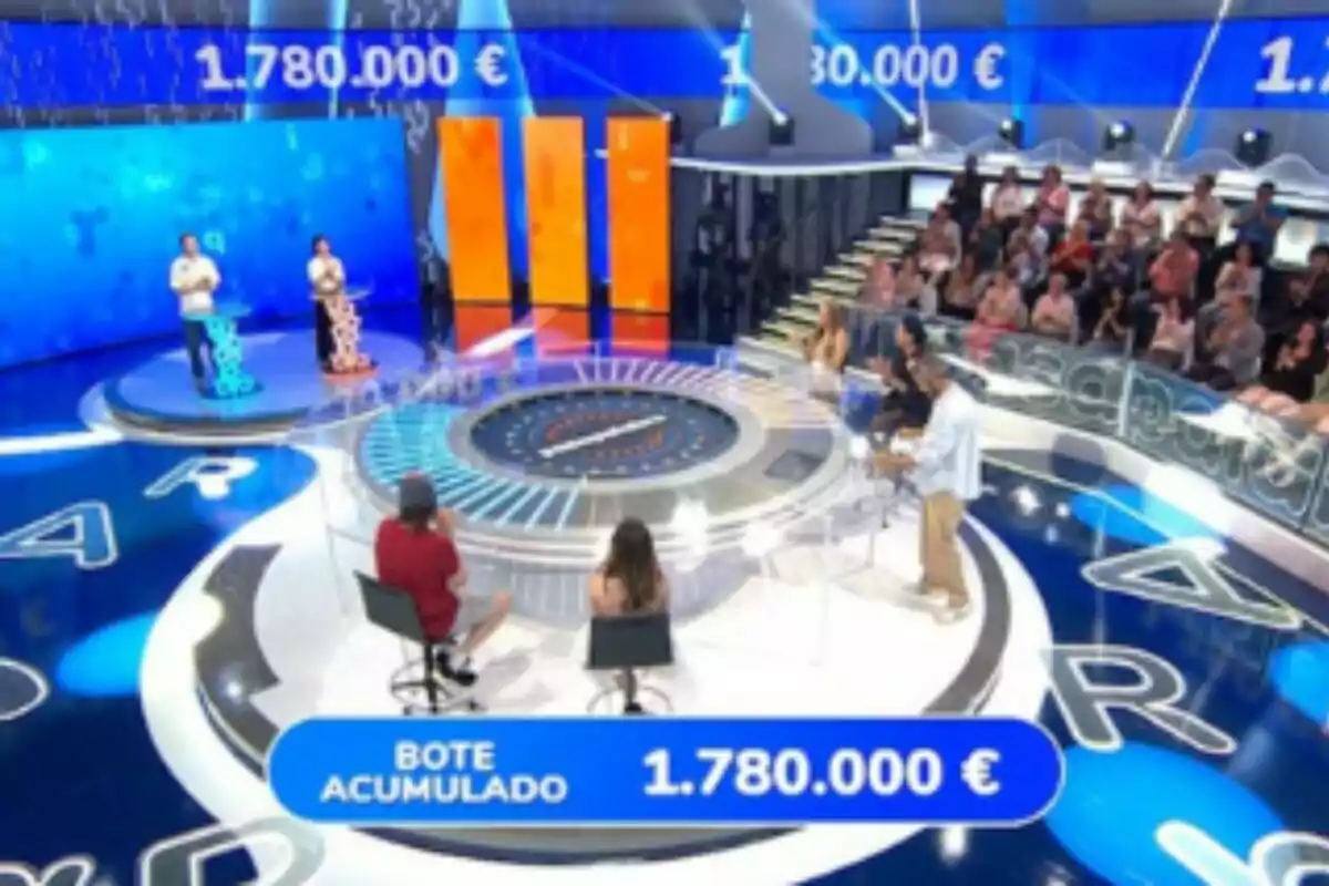 Plató de 'Pasapalabra' con concursantes, público y un marcador que muestra un bote acumulado de un millón setecientos ochenta mil euros. Plató de 'Pasapalabra' con concursantes, público y un marcador que muestra un bote acumulado de un millón setecientos ochenta mil euros.