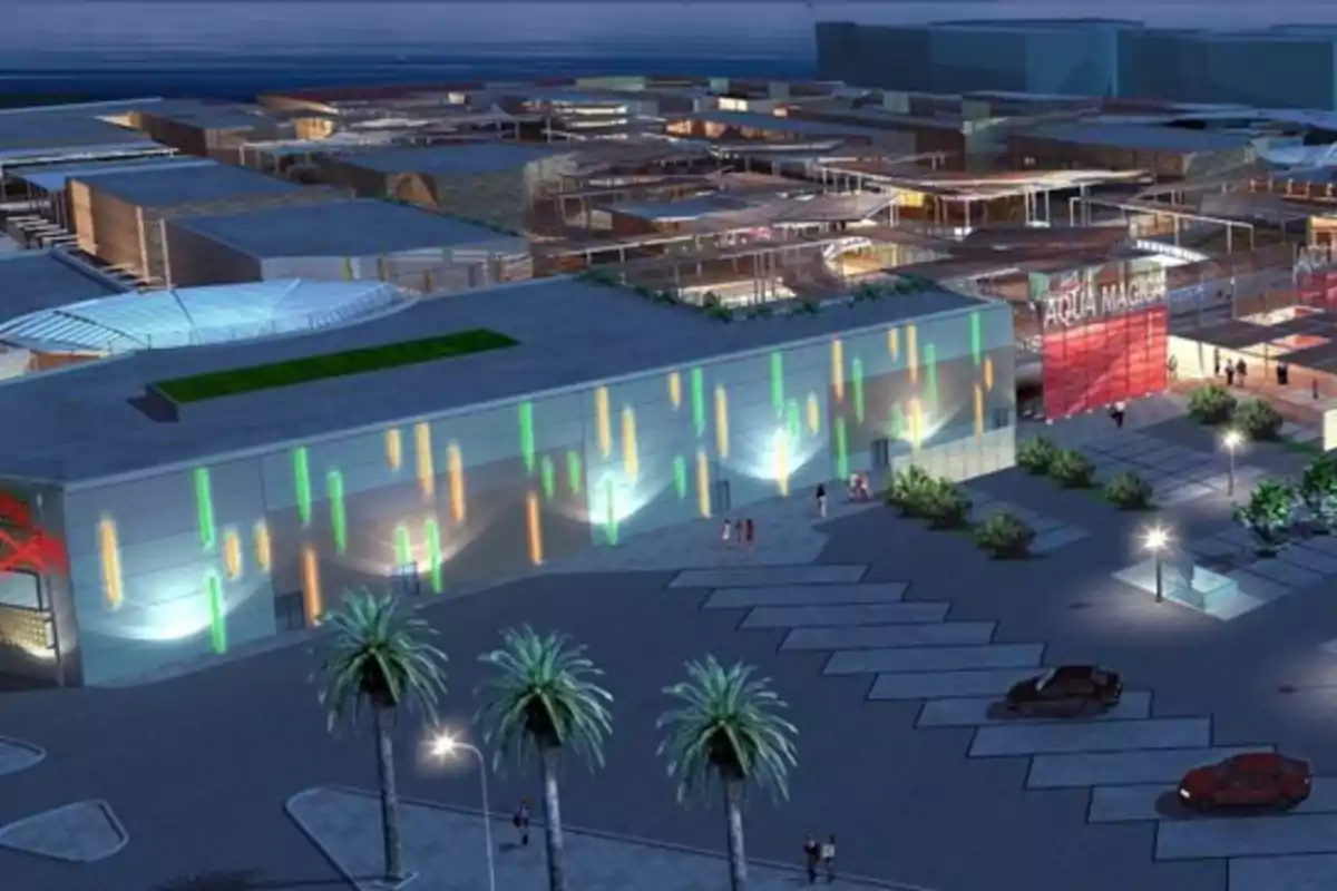 Vista nocturna de un centro comercial moderno con luces de colores en la fachada, palmeras y autos estacionados en el exterior Vista nocturna de un centro comercial moderno con luces de colores en la fachada, palmeras y autos estacionados en el exterior