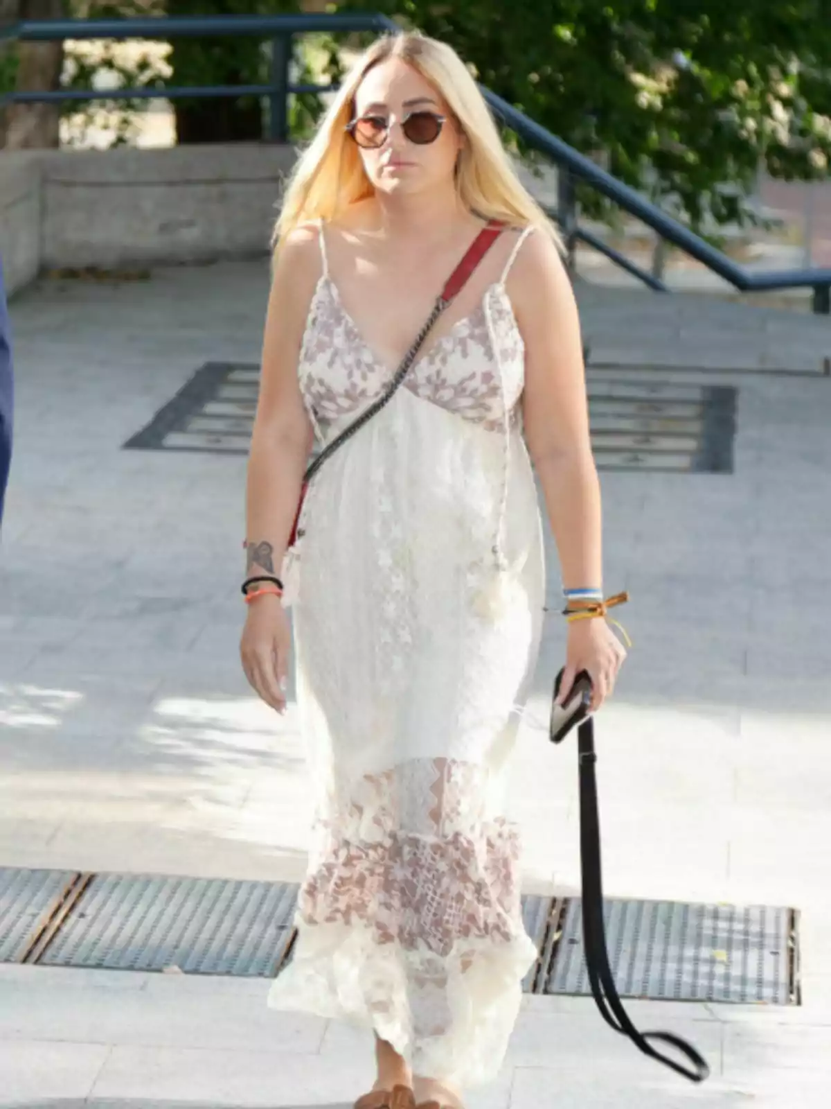 Rocío Flores con gafas de sol y vestido largo blanco con detalles marrones caminando por la calle Rocío Flores con gafas de sol y vestido largo blanco con detalles marrones caminando por la calle