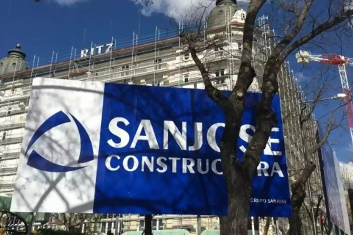 Cartel de la empresa San José Constructora frente a un edificio en remodelación con andamios y una grúa al fondo Cartel de la empresa San José Constructora frente a un edificio en remodelación con andamios y una grúa al fondo