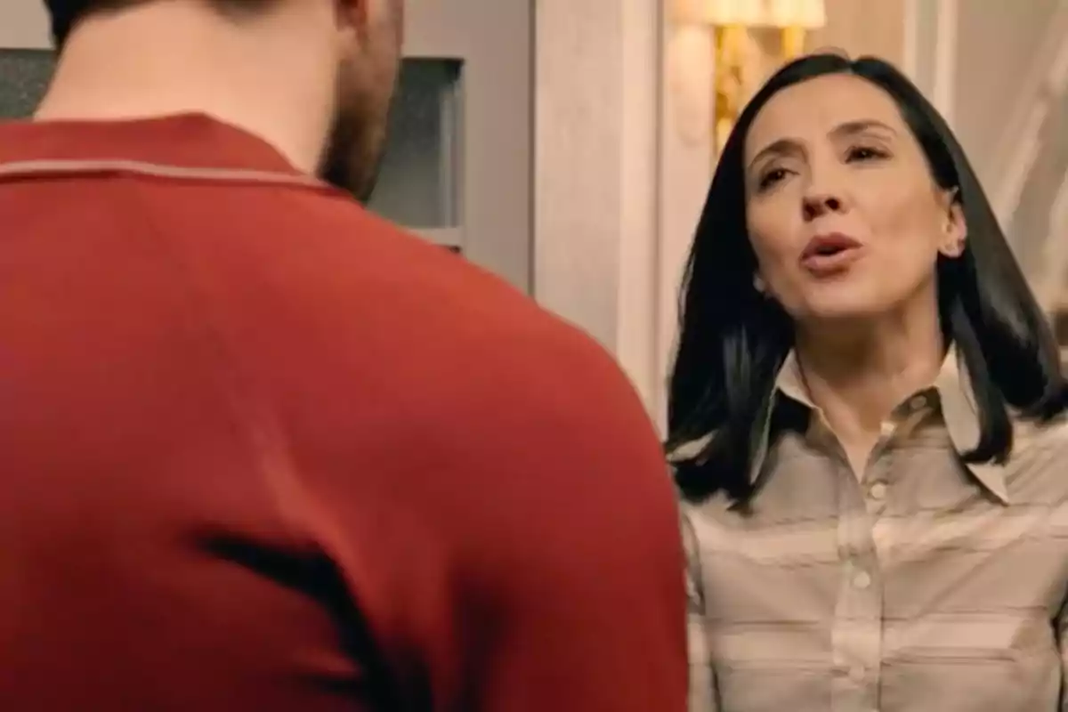 Luz de cabello oscuro y camisa beige habla con un hombre de espaldas que lleva una camiseta roja dentro de una casa. Captura de 'Sueños de libertad' Luz de cabello oscuro y camisa beige habla con un hombre de espaldas que lleva una camiseta roja dentro de una casa. Captura de 'Sueños de libertad'