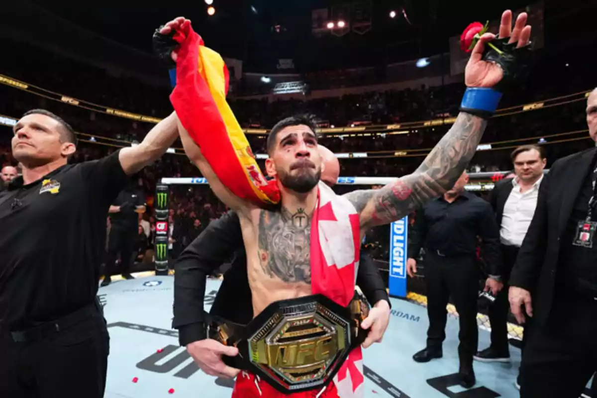 Peleador de artes marciales mixtas celebrando su victoria en el octágono con un cinturón de campeón, una bandera sobre los hombros y una rosa en la mano, rodeado de árbitros y asistentes Peleador de artes marciales mixtas celebrando su victoria en el octágono con un cinturón de campeón, una bandera sobre los hombros y una rosa en la mano, rodeado de árbitros y asistentes