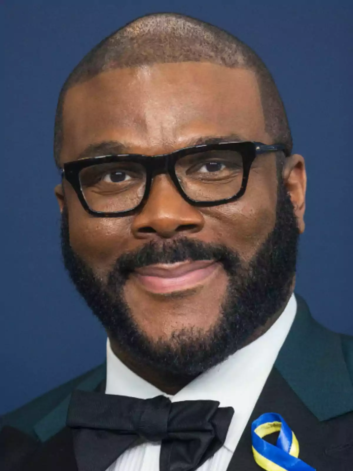 Tyler Perry vistiendo esmoquin y moño negro con un listón azul y amarillo en la solapa Tyler Perry vistiendo esmoquin y moño negro con un listón azul y amarillo en la solapa