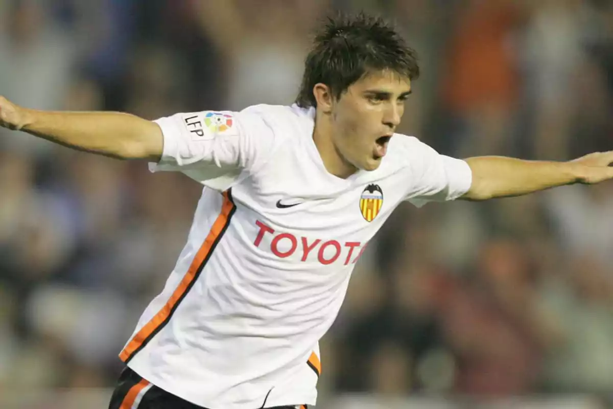 Futbolista celebrando un gol con los brazos extendidos vistiendo el uniforme blanco del Valencia CF Futbolista celebrando un gol con los brazos extendidos vistiendo el uniforme blanco del Valencia CF