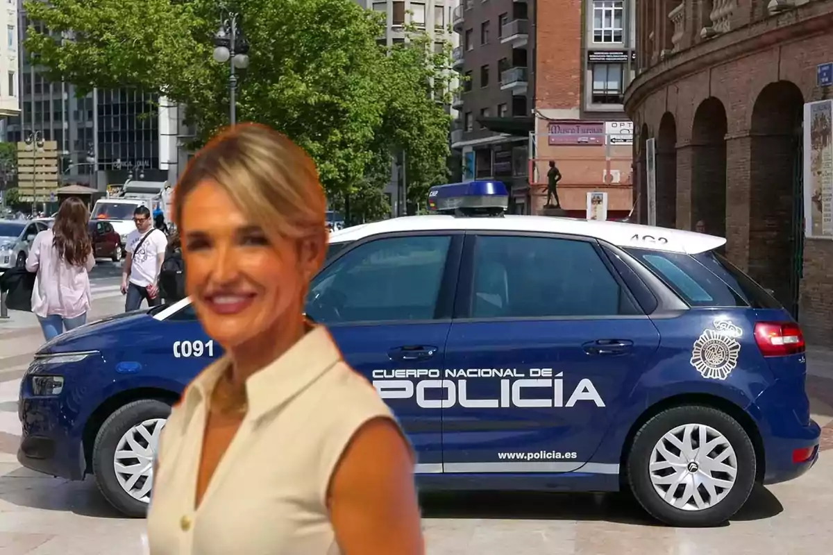 Mujer sonriente en primer plano con un coche de la policía nacional de España estacionado en una calle urbana al fondo