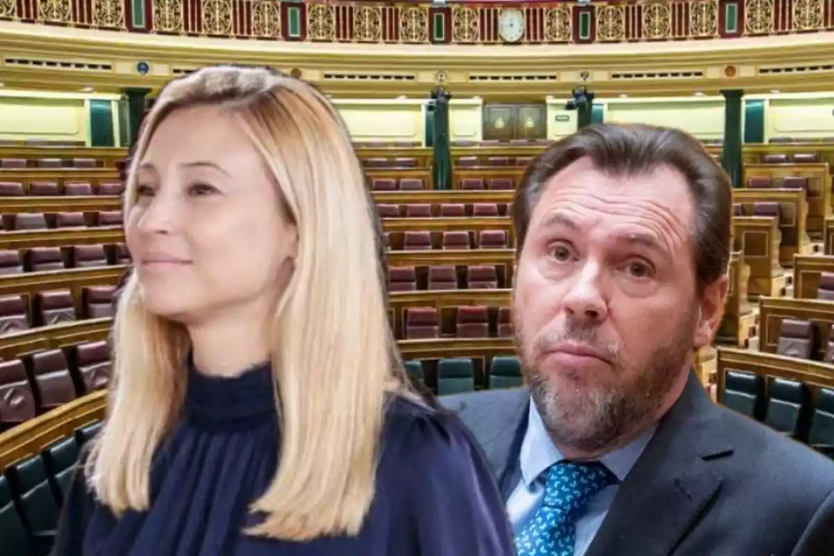 Dos personas en primer plano dentro de un hemiciclo parlamentario con asientos vacíos al fondo