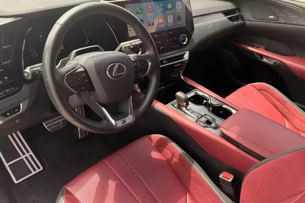 Interior de un auto Lexus con asientos rojos, volante multifunción y pantalla central con sistema de infoentretenimiento Interior de un auto Lexus con asientos rojos, volante multifunción y pantalla central con sistema de infoentretenimiento