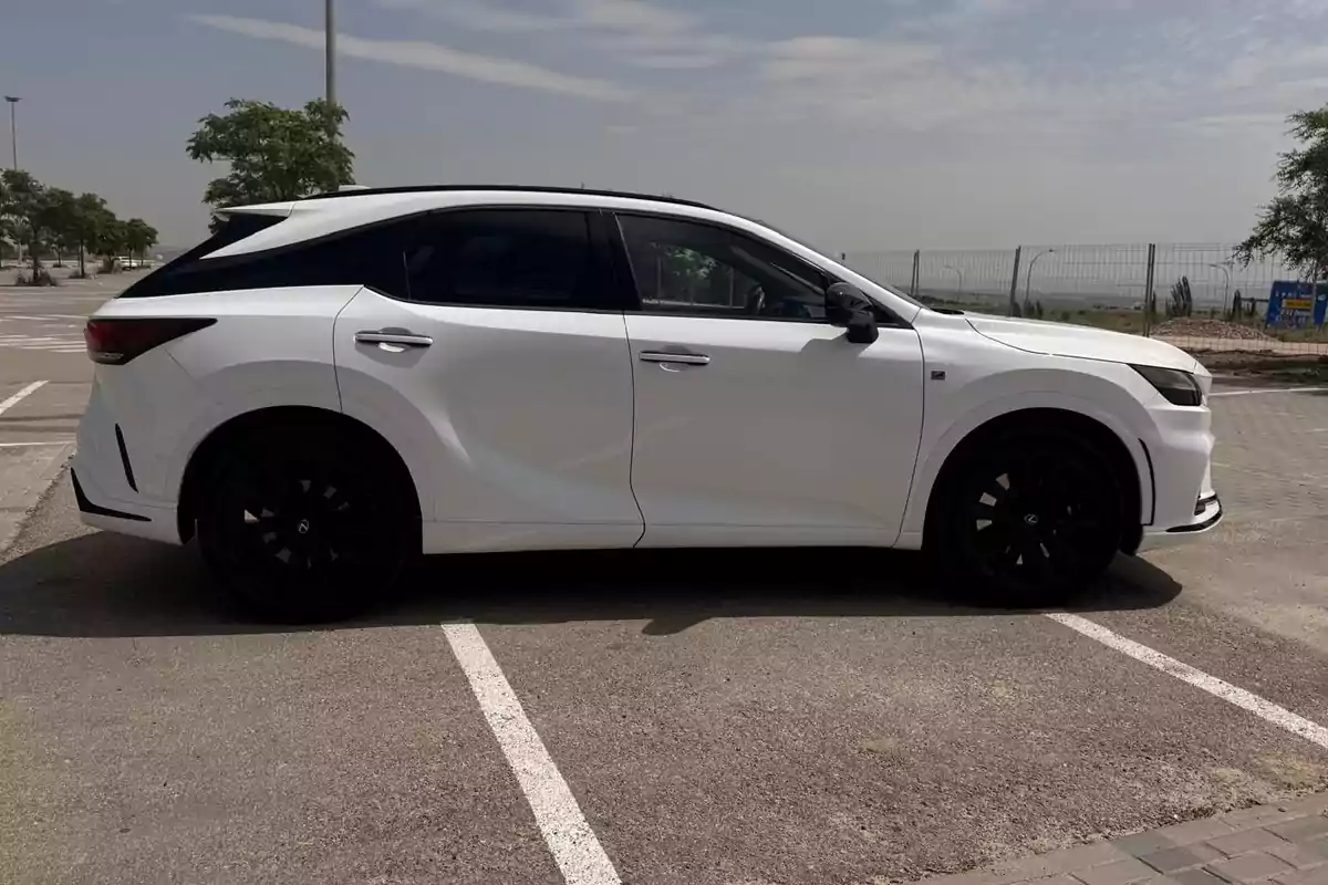 Auto SUV blanco estacionado en un aparcamiento al aire libre en un día soleado Auto SUV blanco estacionado en un aparcamiento al aire libre en un día soleado