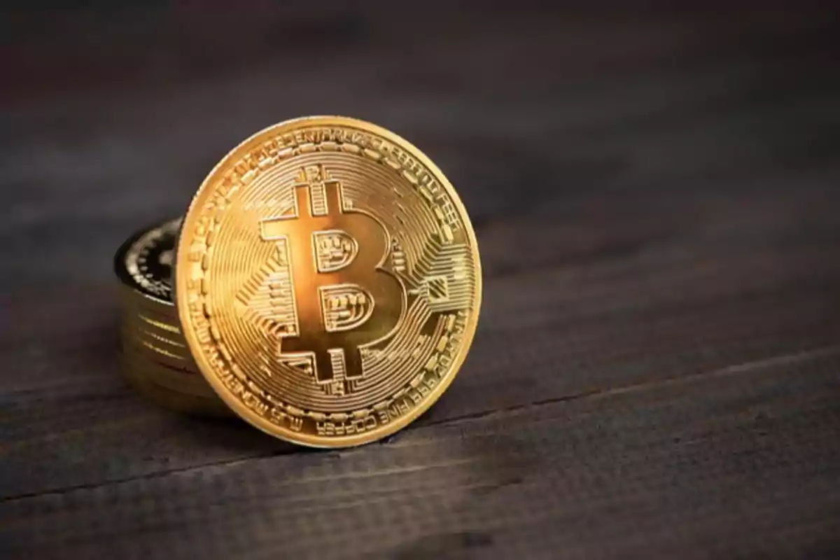 Moneda dorada de bitcoin sobre una superficie de madera