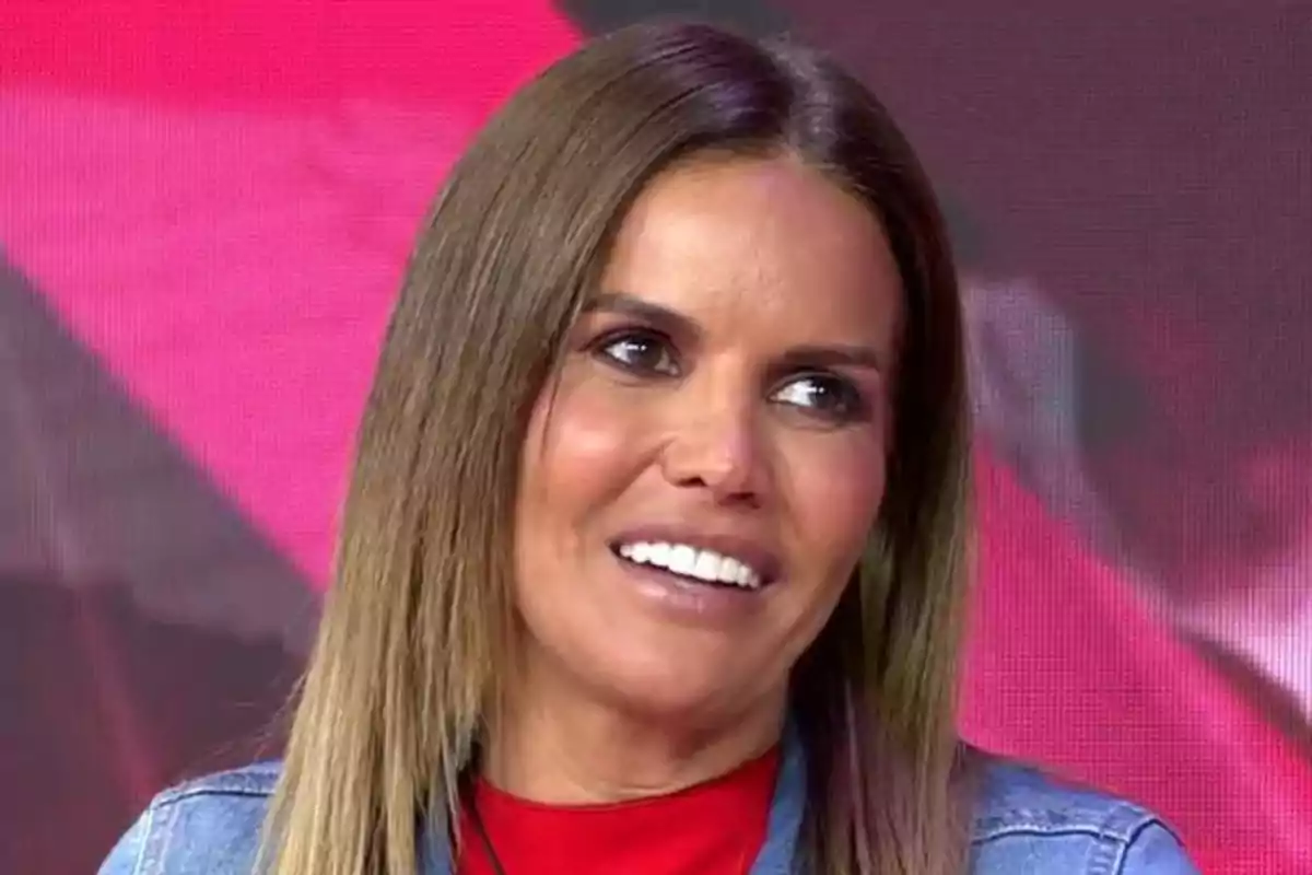 Mujer de cabello lacio y castaño claro sonriendo con fondo de colores rojo y rosa Mujer de cabello lacio y castaño claro sonriendo con fondo de colores rojo y rosa