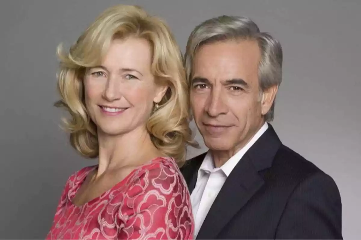 Pareja de personas adultas posando y sonriendo frente a un fondo gris Pareja de personas adultas posando y sonriendo frente a un fondo gris