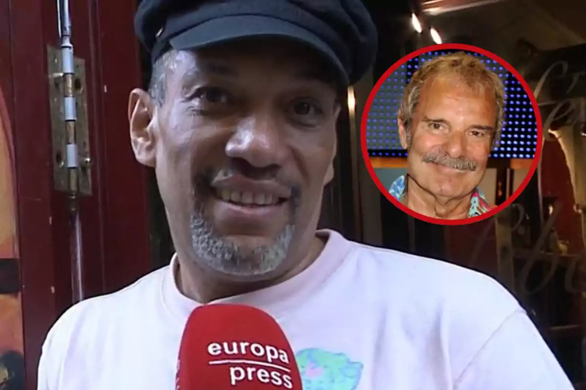 Un hombre con gorra negra y camiseta clara sostiene un micrófono rojo de europa press mientras sonríe, en la esquina superior derecha aparece el retrato de otro hombre mayor con bigote dentro de un círculo rojo.