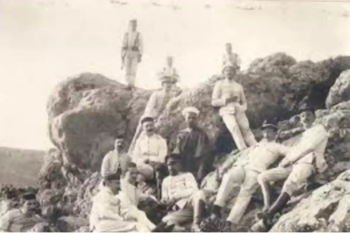Grupo de hombres con uniformes antiguos posando sobre unas rocas en un entorno natural Grupo de hombres con uniformes antiguos posando sobre unas rocas en un entorno natural